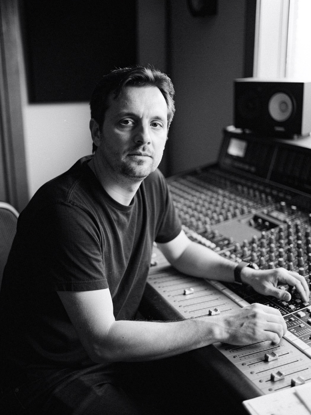 Portrait of a producer at an analogue mixing desk, looking into the camera