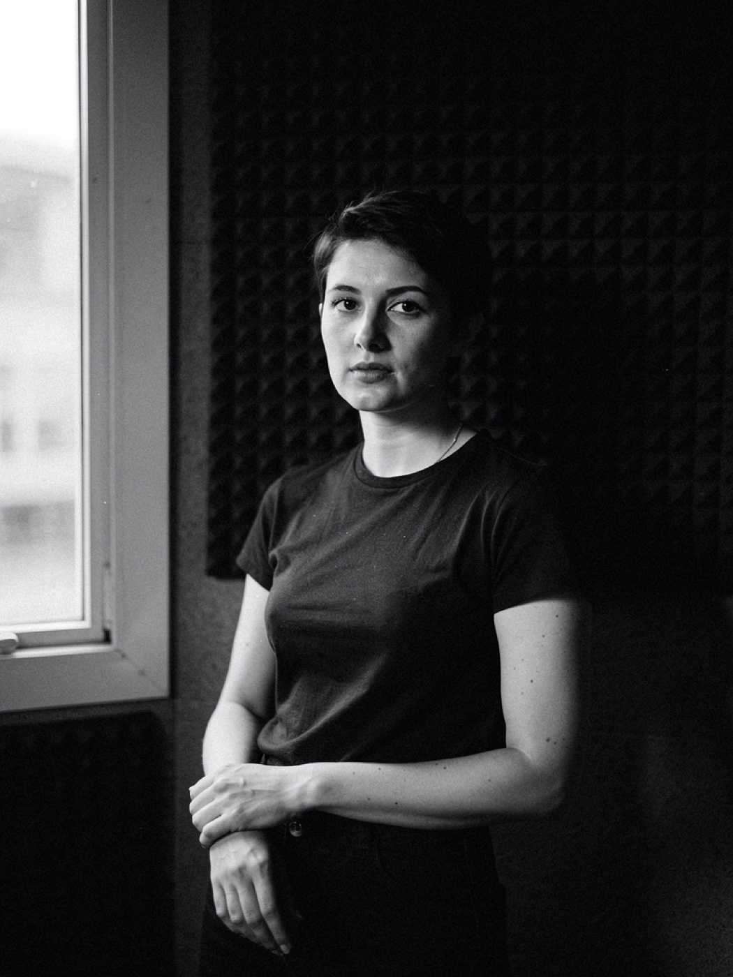 Portrait of a producer against a wall of acoustic foam, half in shadow