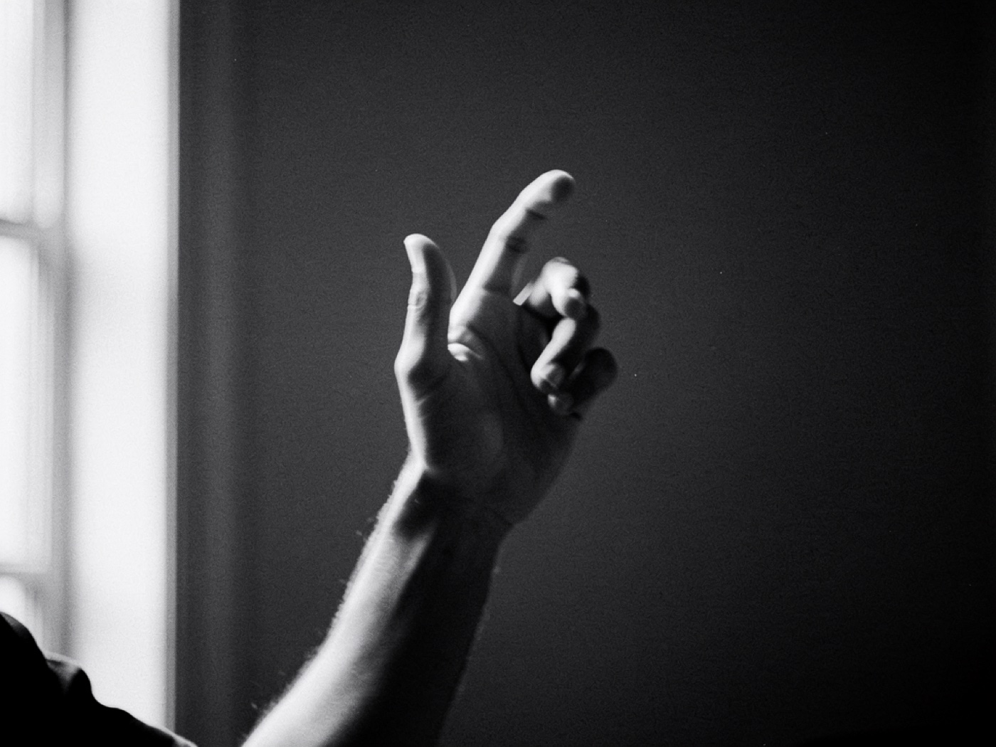 A hand making a conducting gesture against a dark wall